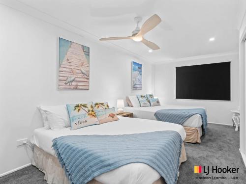 two beds in a hotel room with a flat screen tv at Iluka Magic in Iluka