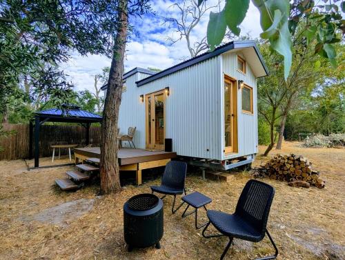 a tiny house with a picnic table and chairs at Little Sheoak Tiny House in Langwarrin