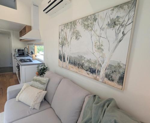 a living room with a couch and a painting on the wall at Little Sheoak Tiny House in Langwarrin