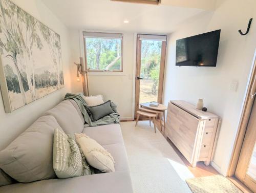 a living room with a couch and a tv at Little Sheoak Tiny House in Langwarrin