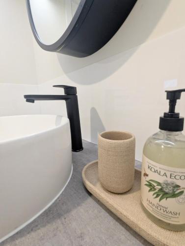 a bathroom with a sink and a bottle of soap at Little Sheoak Tiny House in Langwarrin