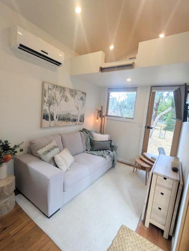 a living room with a white couch and a table at Little Sheoak Tiny House in Langwarrin