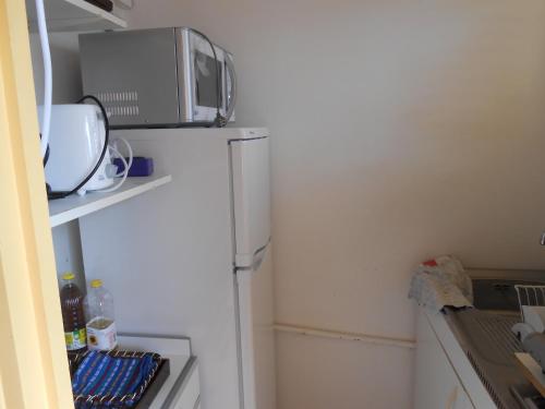a kitchen with a microwave on top of a refrigerator at Entre Mer et Verdure in Sainte-Anne