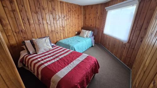 a bedroom with wooden walls and a bed and a window at San Joaquin in Curacautín