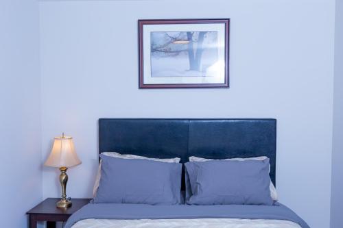 a bed with a blue headboard and a picture on the wall at Honeycomb Suite in Riverview