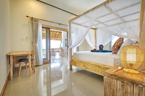 a bedroom with a canopy bed and a table at Arungan Villas in Amed