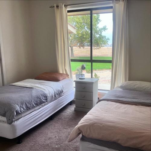 a bedroom with two twin beds and a window at Wings Field - relaxing family farm stay in Tocumwal