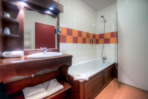 a bathroom with a tub and a sink and a mirror at Zenitude Hôtel-Résidences Les Terrasses du Lac in Évian-les-Bains