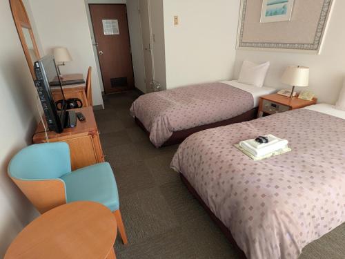 a hotel room with two beds and a television at Kagetsuen in Hakone