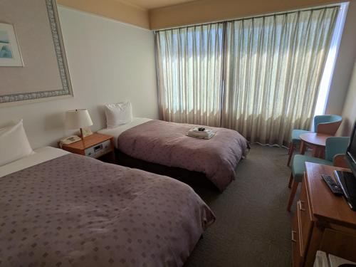 a hotel room with two beds and a window at Kagetsuen in Hakone