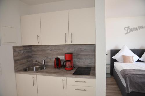 a kitchen with white cabinets and a sink and a bed at Seebrise mit Musik und Wein in Meersburg