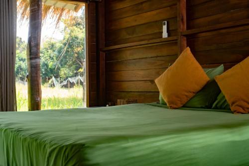 a bedroom with a green bed with a window at Raintree Haven in Dambulla