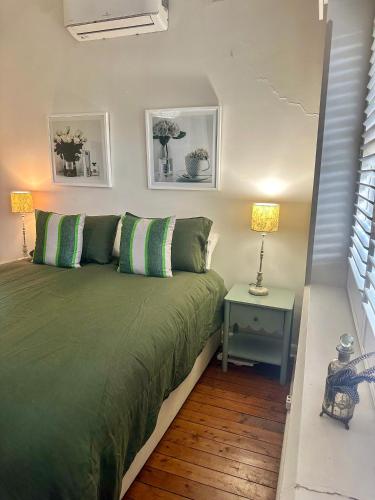 a bedroom with a green bed and a table with a lamp at Darlow Cottage in Wagga Wagga