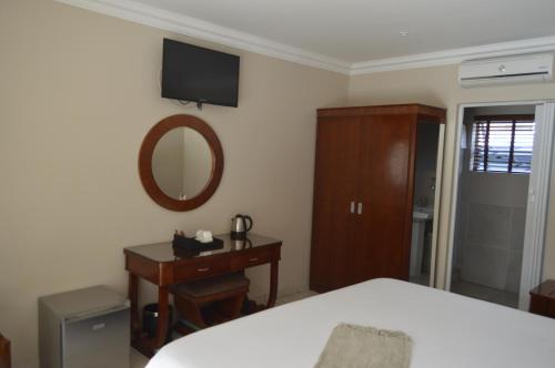 a bedroom with a bed and a dresser and a mirror at Lakeview Boutique Hotel & Conference Center in Benoni