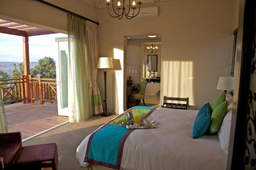 a bedroom with a large bed and a balcony at Mount Grace Hotel & Spa in Magaliesburg