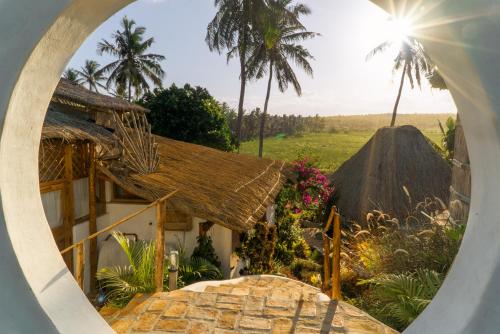 a view of a house through a round window at Sunset View Tofo in Praia do Tofo