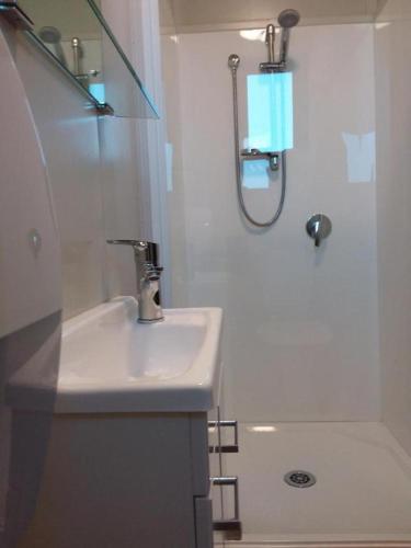 a white bathroom with a sink and a shower at Pineacres Motel and Park in Kaiapoi