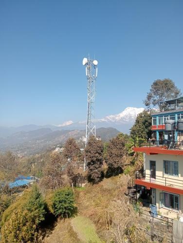 una casa su una collina con una torre per telefoni cellulari di Dawn view lodge a Pokhara