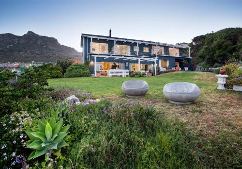 a house with three stone seats in a garden at Poseidon Guest House in Hout Bay
