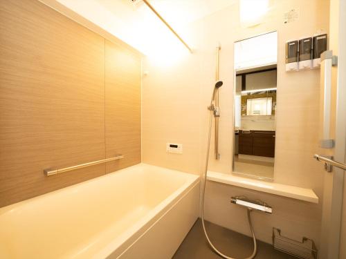 ein Badezimmer mit Badewanne und Spiegel in der Unterkunft いけだ屋 in Kōzai
