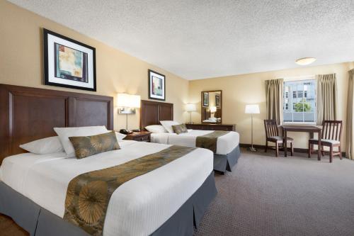 a hotel room with two beds and a desk at Travelodge by Wyndham San Francisco Bay in San Francisco