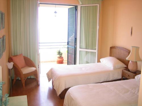 a hotel room with two beds and a chair at Apartamento do Sol in Arco da Calheta