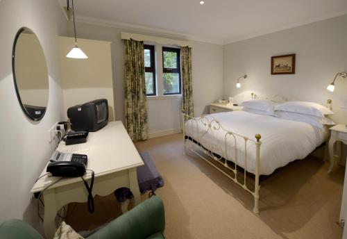 a bedroom with a bed and a desk with a computer at The Factor's Inn & Factor's Cottage in Fort William