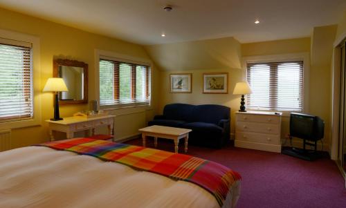 a bedroom with a bed and a chair and a television at The Factor's Inn & Factor's Cottage in Fort William