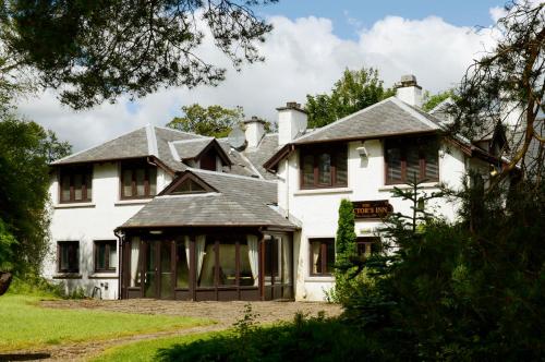 Casa blanca grande con persianas marrones en The Factor's Inn & Factor's Cottage, en Fort William