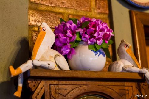 a vase filled with purple flowers on top of a shelf at Pousada Romântica Serra da Mata in Penedo