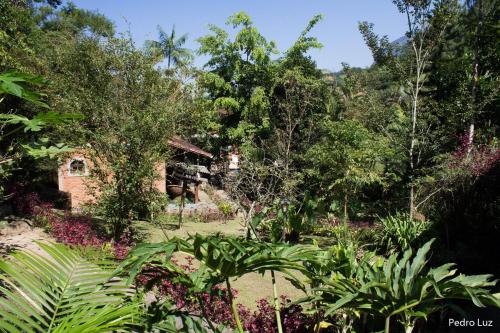 a garden in front of a house with trees at Pousada Romântica Serra da Mata in Penedo
