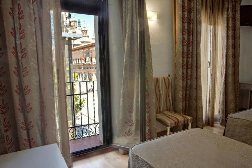 a room with a balcony with a large glass door at Hotel Tibur in Zaragoza