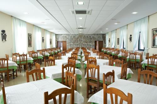 a room filled with tables and chairs with white tablecloths at Hospederia Monasterio de Poio in Poio