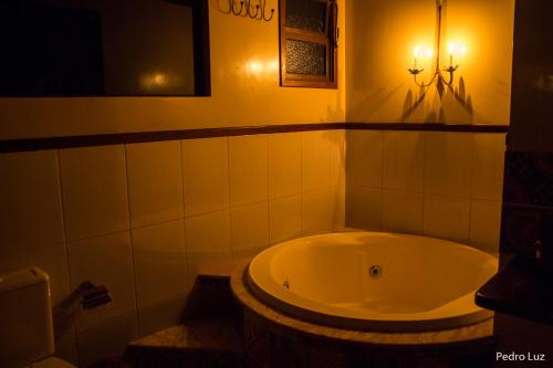 a bathroom with a tub and a light on the wall at Pousada Romântica Serra da Mata in Penedo