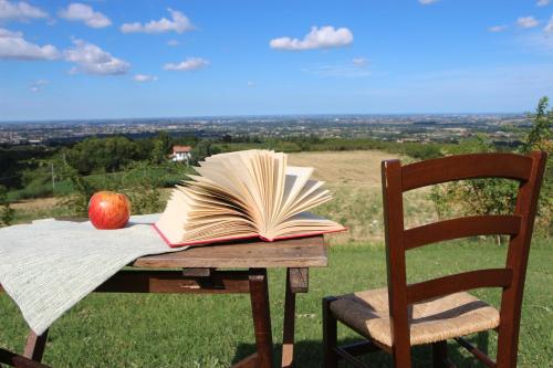 an open book on a table with an apple and a chair at R&B Del Monte in Forlì