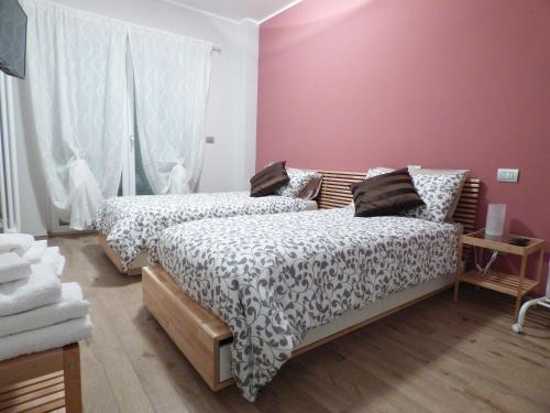 - 2 lits dans une chambre aux murs roses dans l'établissement Giravento, à Borgo San Dalmazzo