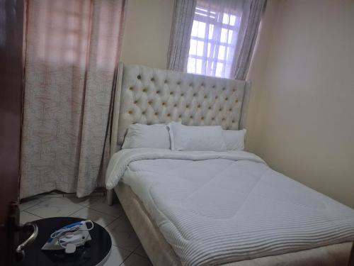 a bedroom with a large white bed with a window at Texas Apartments 1 Bedroom bnb Thika in Thika