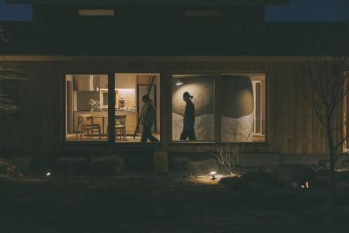 a couple of people standing in a window at night at Peanuts Nest in Nagano