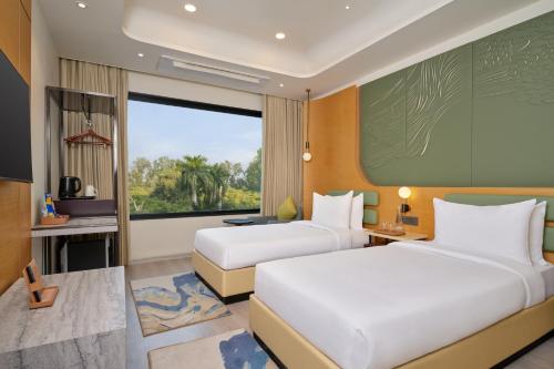 a hotel room with two beds and a window at Varay Grande in Ujjain
