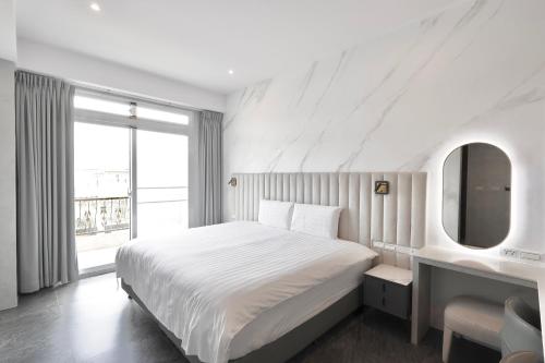 a white bedroom with a large bed and a window at 芙蘿拉萃旅 in Taitung City