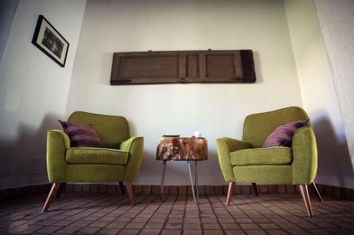 two green chairs and a table in a room at Bosco Ciancio in Biancavilla