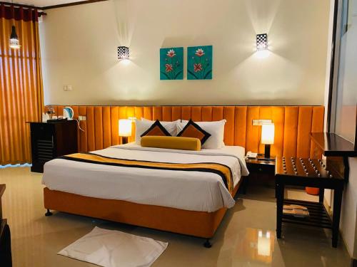 a bedroom with a large bed and a desk and lamps at Laya Beach in Wadduwa