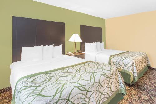 a hotel room with two beds and a lamp at Baymont by Wyndham Holland in Holland