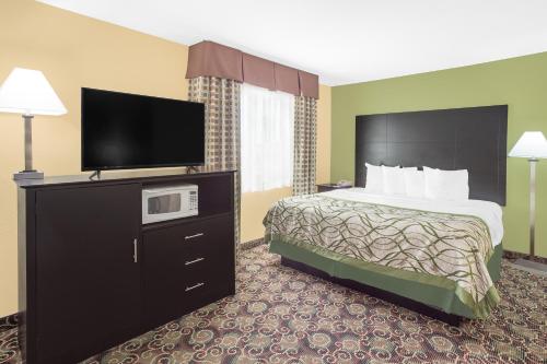 a hotel room with a bed and a flat screen tv at Baymont by Wyndham Holland in Holland