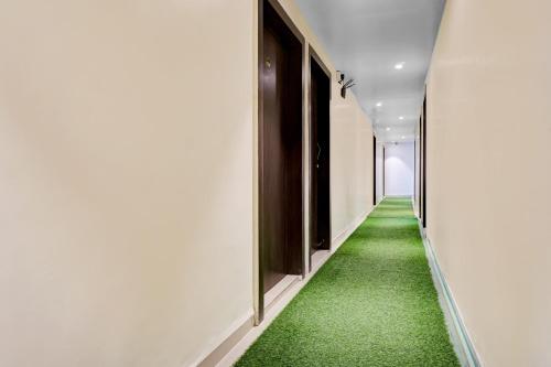 an aisle with green carpet in a hallway at Hotel O Parinda Lodging in Chinchwad