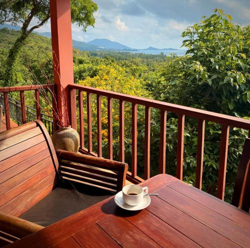 a cup of coffee sitting on a wooden table on a balcony at PawPaw Resort in Lamai