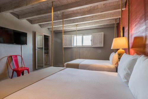 克雷塔羅的住宿－Hotel Damiana Boutique，一间卧室配有一张床和一张红色椅子