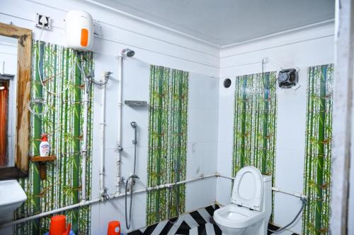 a bathroom with a toilet and green shower curtains at Banalata Resort in Jaypur