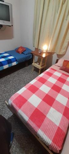a room with two beds and a table and a tv at Departamento PyA in San Miguel de Tucumán