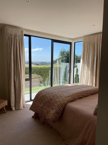 a bedroom with a bed and a large window at Perfection on Park Lane in Timaru